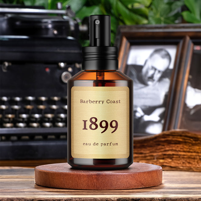 Barberry Coast 1899 Eau de Parfum Cologne. Standard 2oz amber bottle with spray cap with a typewriter and picture frame of Ernest Hemingway in the background.