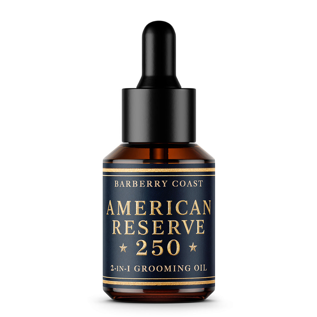 American Reserve 250 2-in-1 grooming oil bottle by Barberry Coast, featuring an amber glass bottle, a black dropper cap, and a navy blue label with gold lettering.