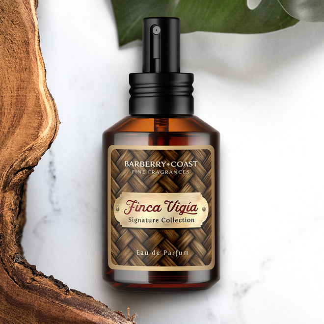 Photo of Finca Vigia Eau de Perfume Cologne by Barberry Coast on white marble background. Standard 2oz clear amber-colored apothecary bottle with a black atomizer sprayer cap. Inspired by Ernest Hemingway's home in Havana, Cuba.