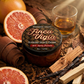 Jar of Finca Vigia Supreme Shave Cream surrounded by grapefruit, cedarwood, sandalwood, vanilla beans, leather, and a glass of bourbon.