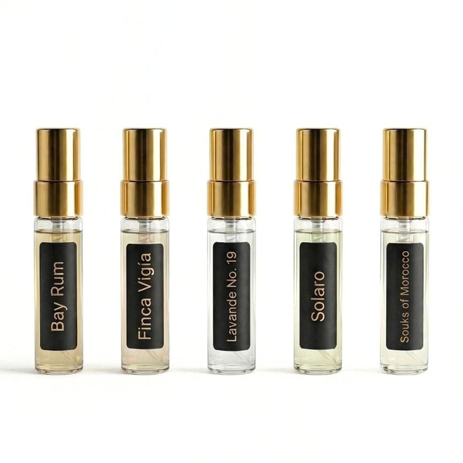 Five small fragrance bottles with gold caps on a white background. Barberry Coast Founder's Selection Fragrance Discovery Set.