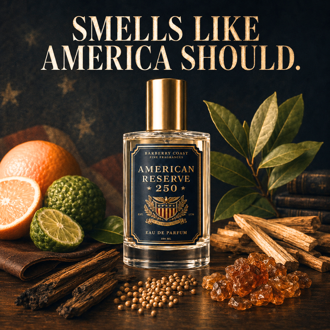 A perfume bottle labeled 'American Reserve 250' stands on a dark wooden surface with citrus fruits, cinnamon sticks, seeds, and amber resin around it. Large text at the top reads 'SMELLS LIKE AMERICA SHOULD.