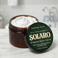 Jar of Solaro Supreme Shave Cream with green lid on a marble surface