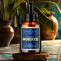 A bottle of Souks of Morocco Eau de Parfum cologne by Barberry Coast with a Moroccan themed background, tropical plants and blue tiled walls and floor.