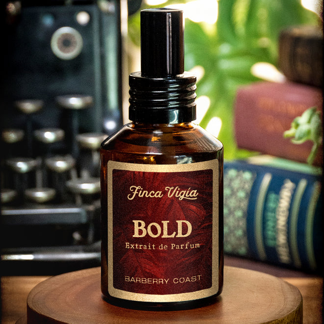 Barberry Coast Finca Vigía Bold Extrait de Parfum Cologne (3.5X more concentrated than Finca Vigía EDP). Standard 2oz amber bottle with an atomizer sprayer cap photo on wood surface and typewriter and books background.