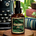 Nature Isle EDP cologne - clear amber apothecary style cologne bottle on a wood surface with a typewriter and books in the background